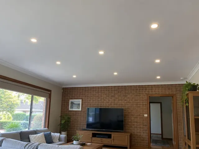 Living room ceiling with recessed downlights above a brick feature wall and sofa in Frenchs Forest