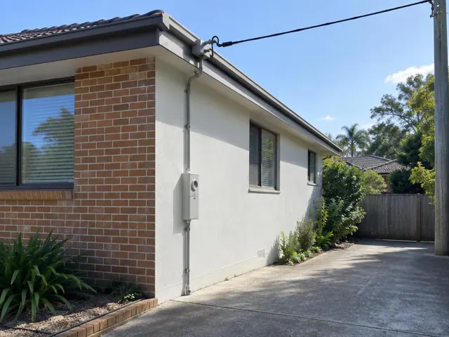 Brick and rendered house exterior with overhead service cable and point-of-attachment bracket on the eave in Belrose