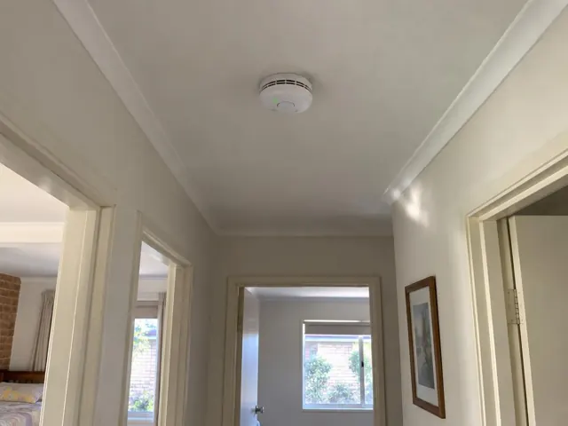 Hallway ceiling smoke alarm in a cream-painted home interior in Davidson